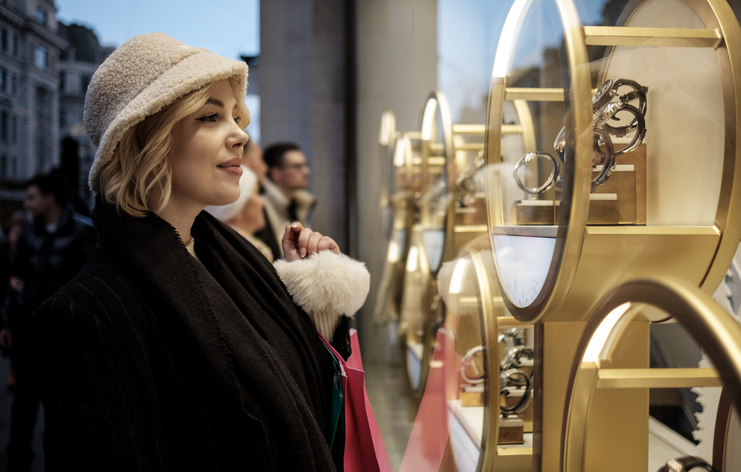 young woman is looking at a window shop jewelry.