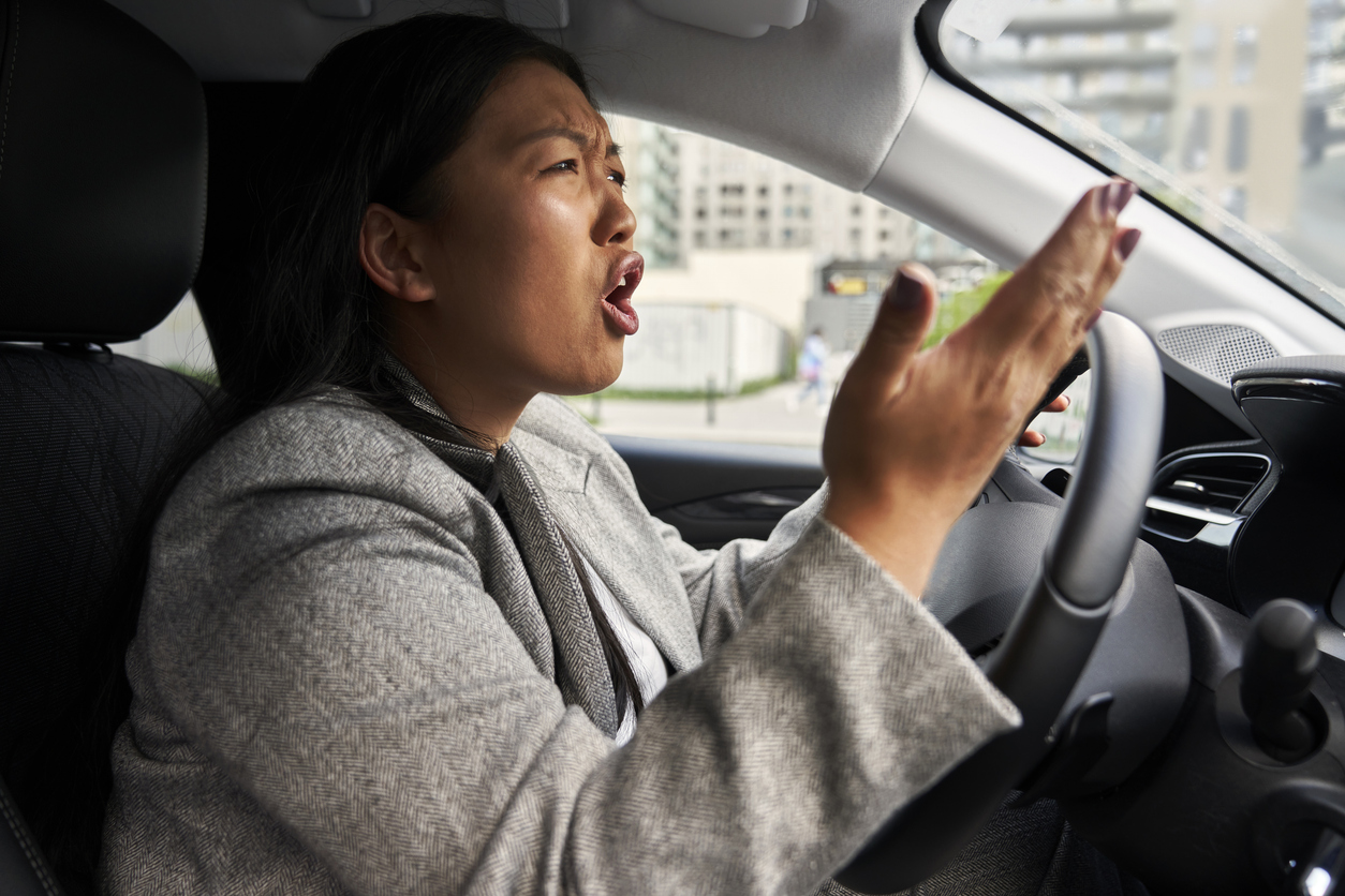 frustrated chinese woman screaming while driving a car