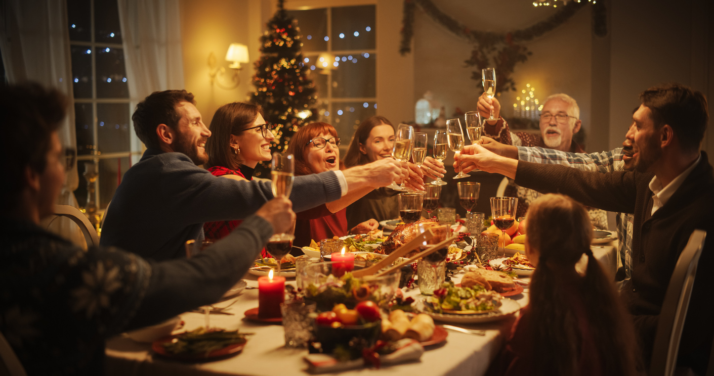 portrait of a handsome young black man proposing a toast at a christmas dinner table. family and friends sharing meals, raising glasses with champagne, toasting, celebrating a winter holiday