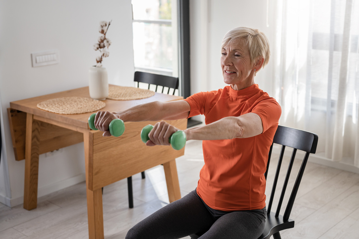 smiling beautiful senior woman health instructor doing chair exercises