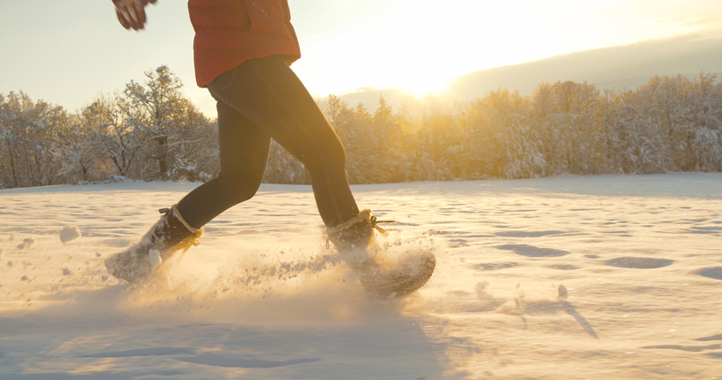 lens flare, close up: unrecognizable young woman runs and sprays fresh snow