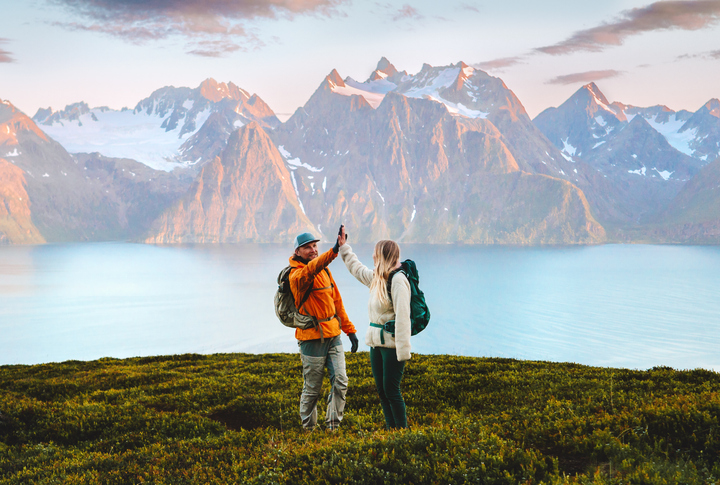 couple friends high five hands on mountain top man and woman backpackers travel together hiking in norway, active vacations outdoor family adventure lifestyle sustainable tourism, teamwork concept