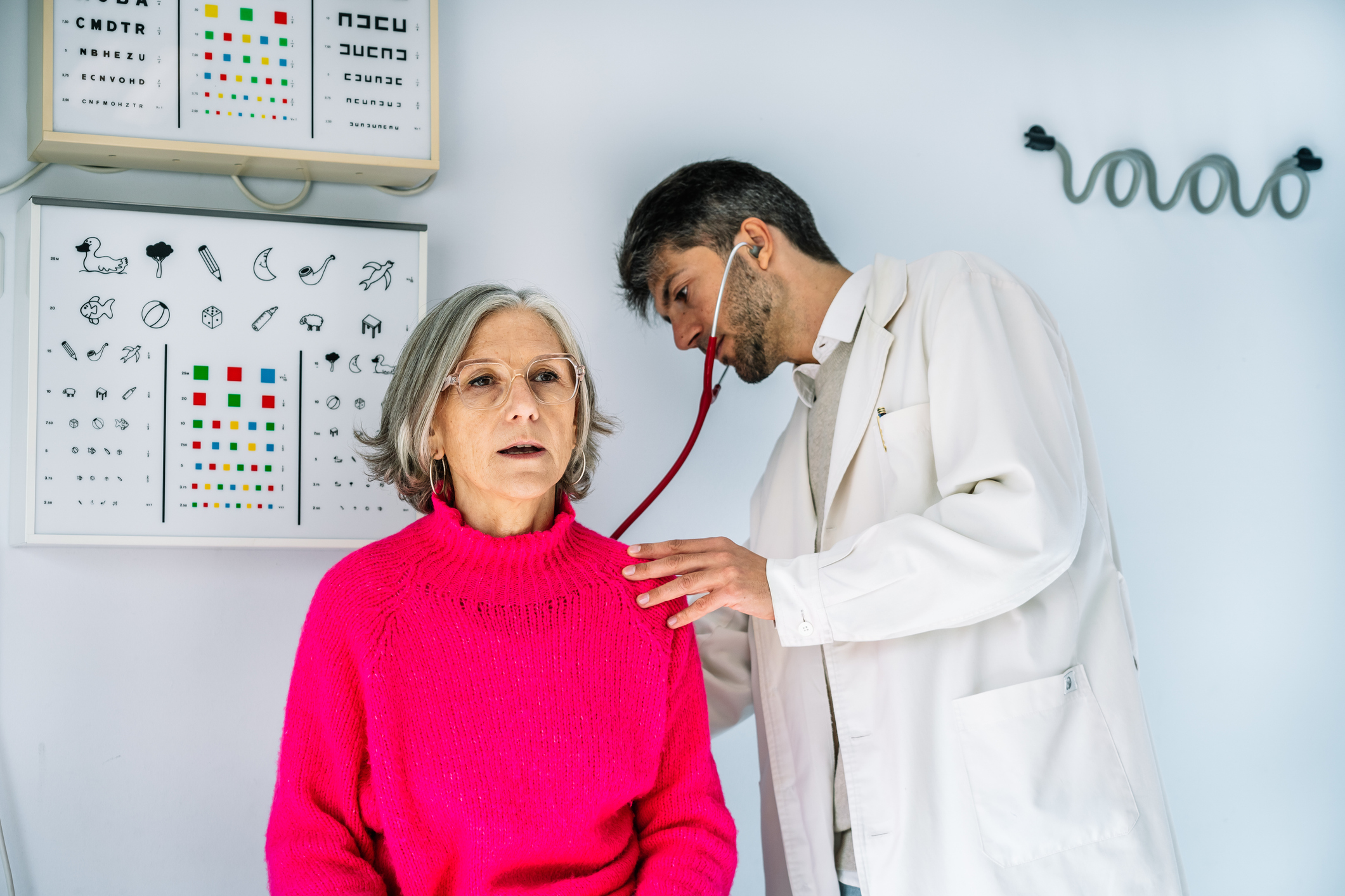 doctor examining senior woman with stethoscope in medical clinic
