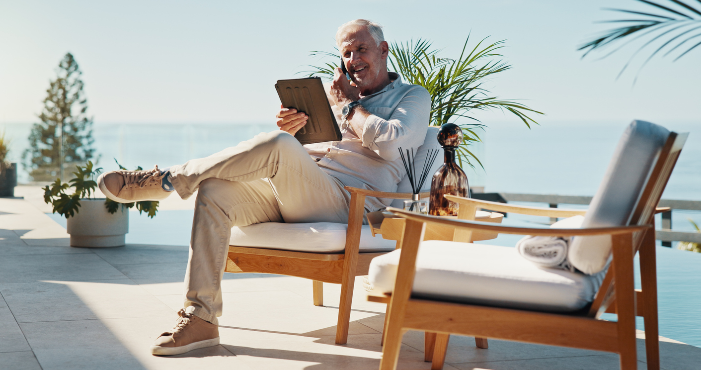 phone call, tablet and relax with man at swimming pool for remote work, resort critic and customer feedback. reading, freelancer and hospitality review with mature person at villa for luxury travel