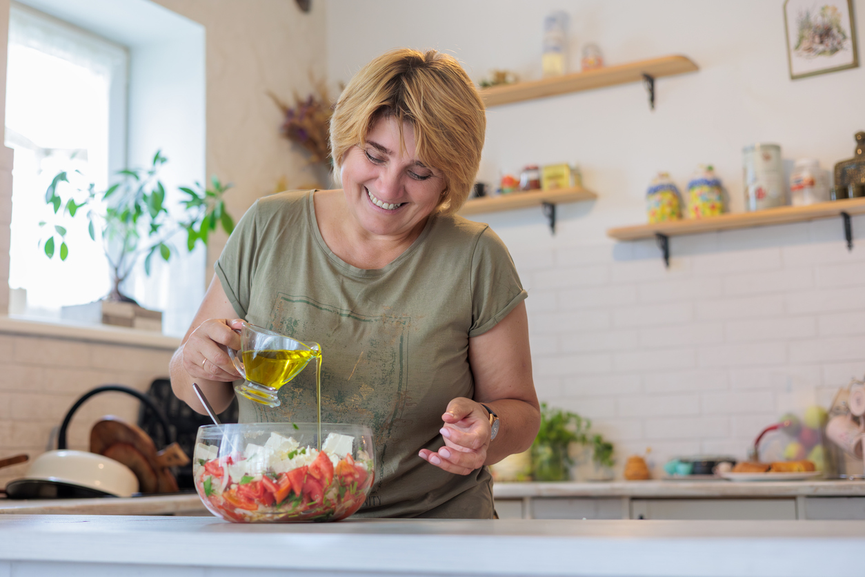 smiling mature woman prepares a healthy salad. lifestyle, nutrition, and self care for women.