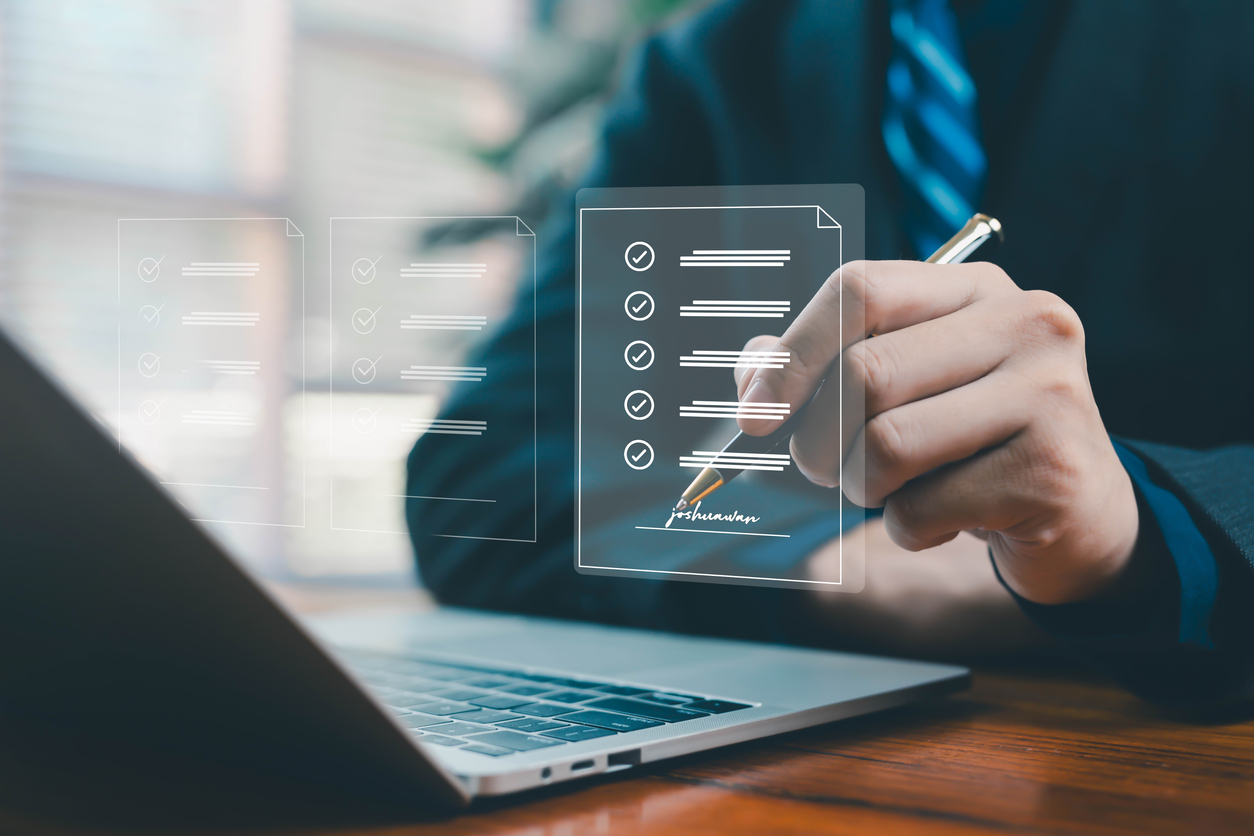 a businessman signing a virtual checklist document above a laptop, symbolizing digital approval, online verification, workflow management, and secure electronic documentation in modern workplaces.
