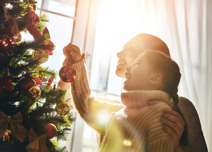 mom and daughter decorate the christmas tree