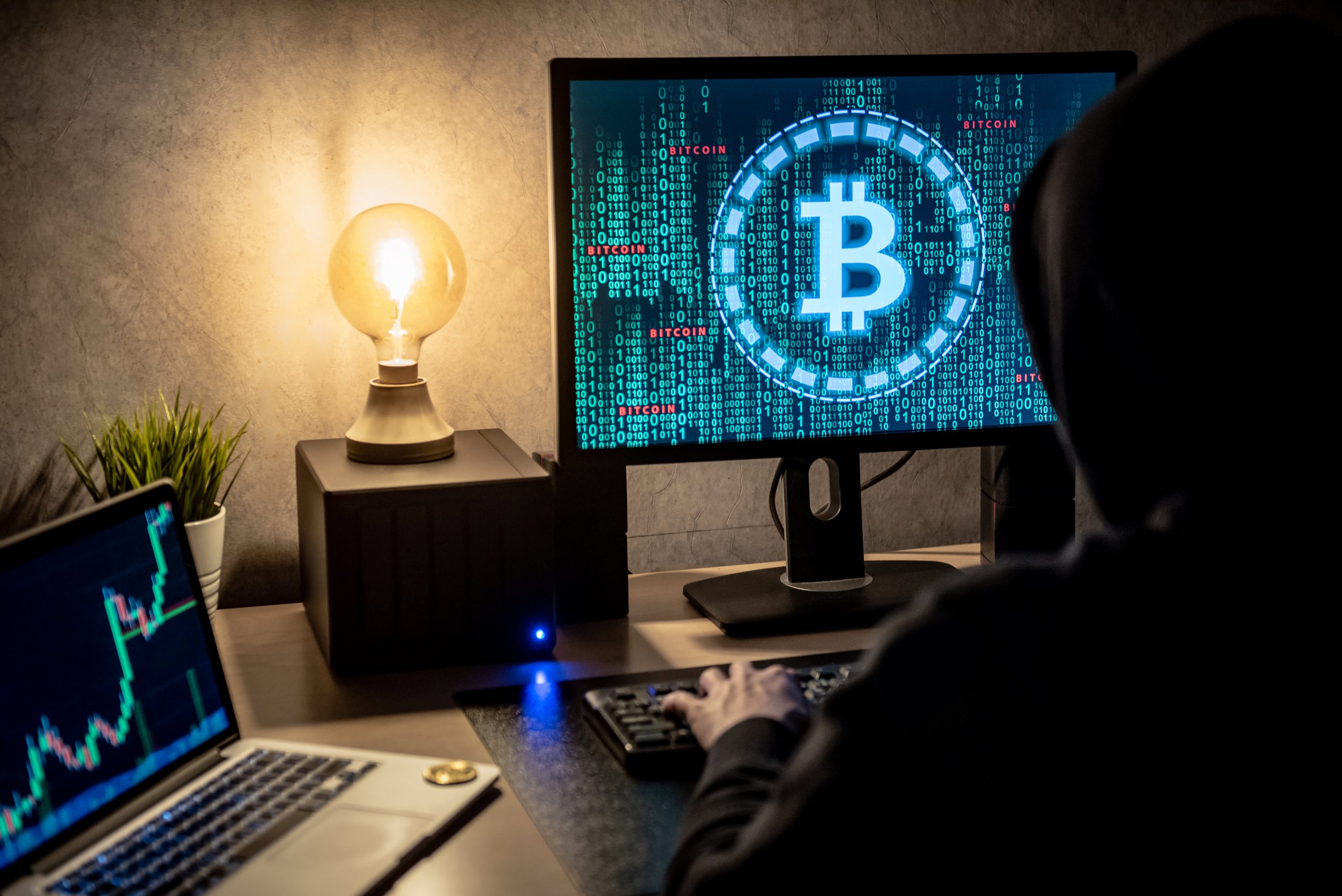 Person at a desk looking at a computer screen showing a Bitcoin symbol and blockchain data, illustrating the difficulty of recovering lost cryptocurrency.