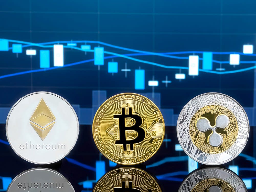 Bitcoin, Ethereum and XRP coins displayed in front of a digital trading chart, symbolising cryptocurrency market volatility and institutional adoption.