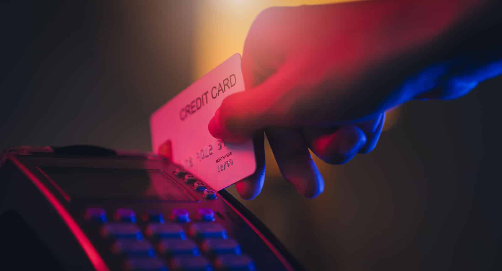 A credit card held tightly in a person&rsquo;s hand under dramatic lighting, symbolizing growing pressure on consumer credit access amid rising bank profits and regulatory scrutiny.