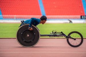 asian young man para athletes disabled practice handcycling in stadium. attractive amputee male runner exercise and practicing workout for paralympics competition regardless of physical limitations.