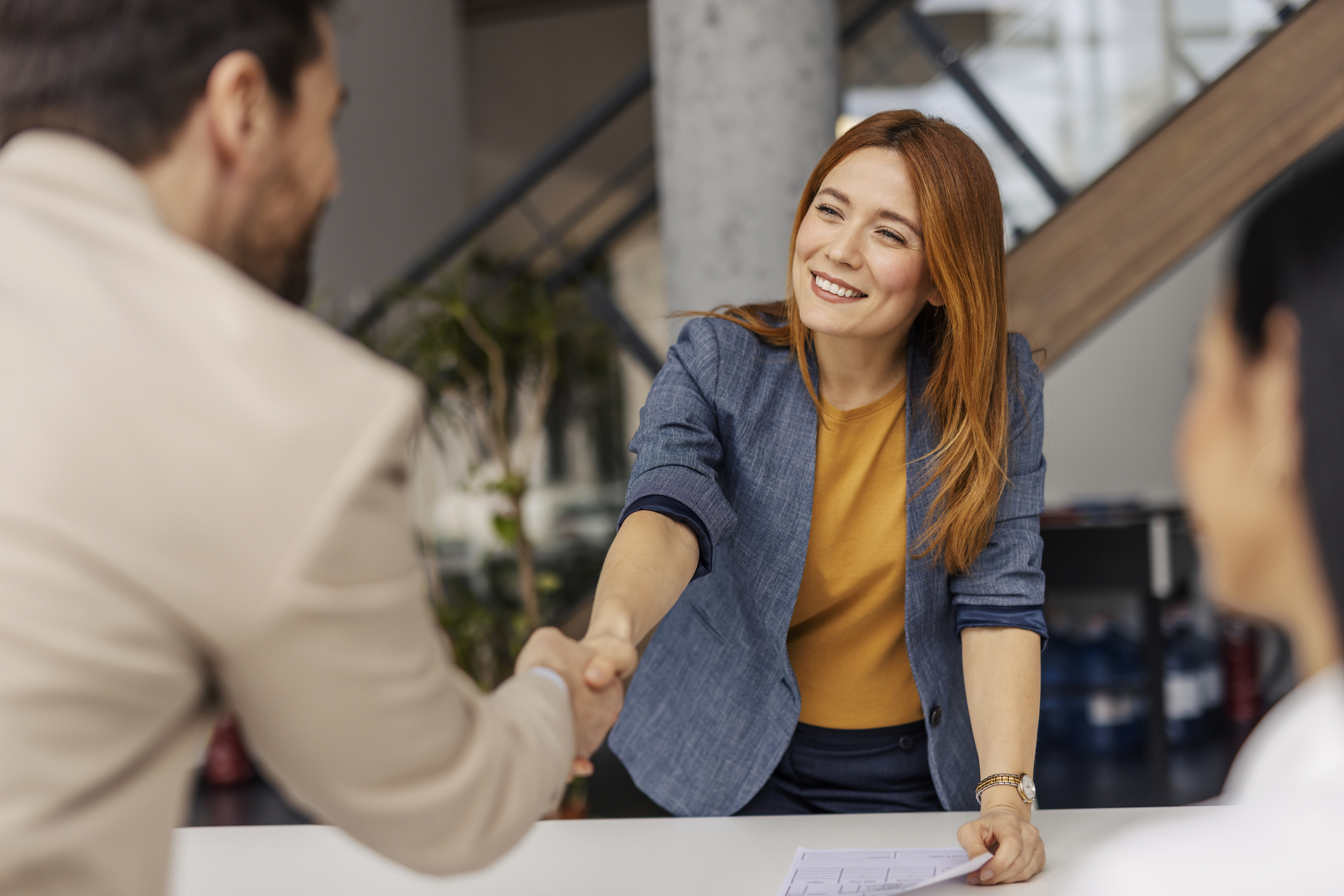 portrait of friendly female boss shaking hands with new team member on sprint meeting.