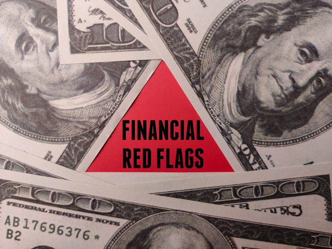 the red triangle with word financial red flags on a hundred dollars