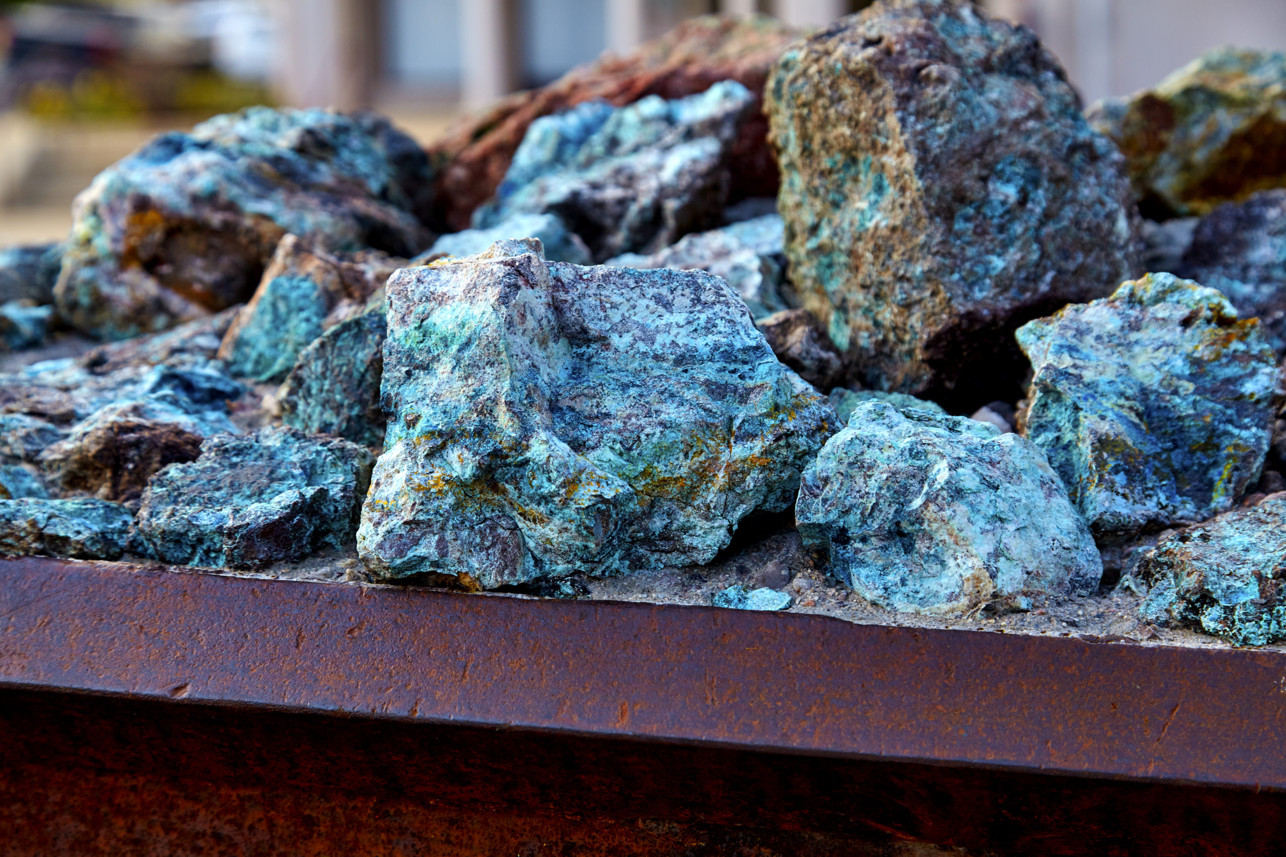 Close-up of copper ore rocks showing blue-green mineral oxidation at an industrial mining site