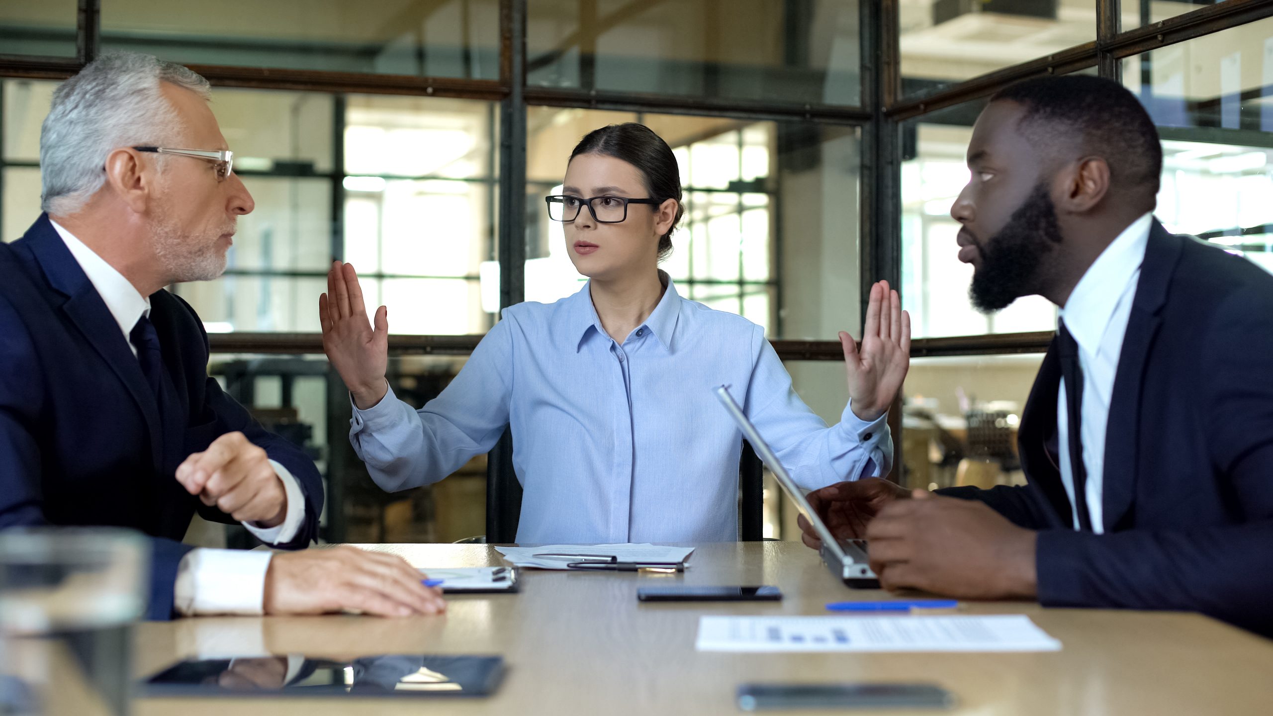 female manager showing stop sign to arguing workers office, conflict resolution
