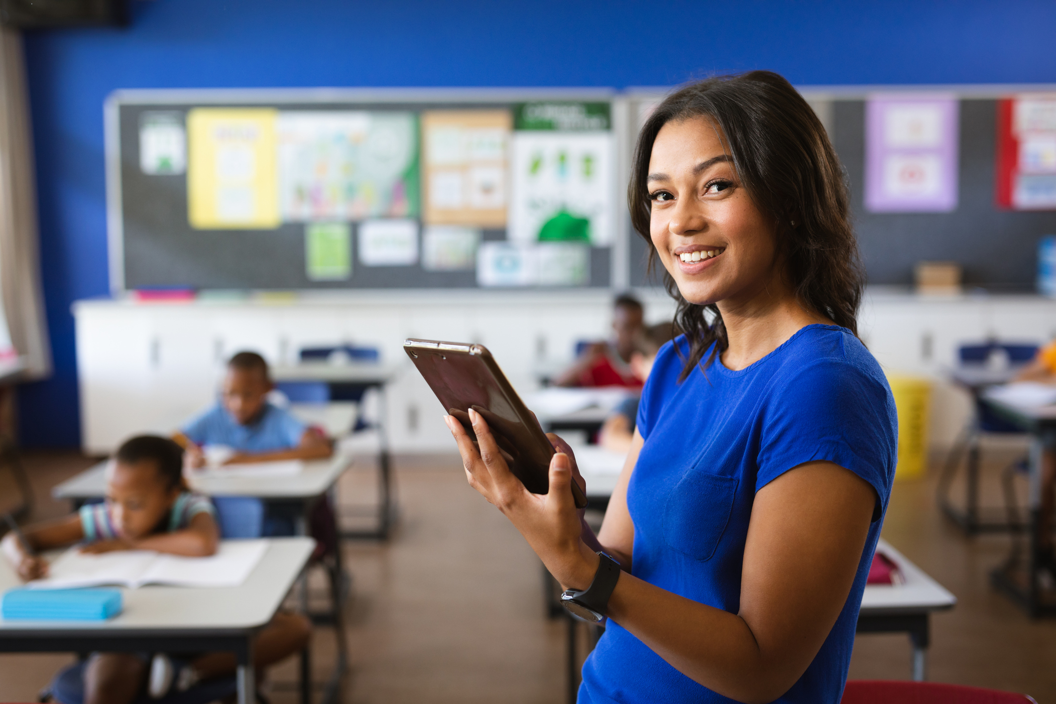 portrait of african american female teacher holding digital tablet in the class at school